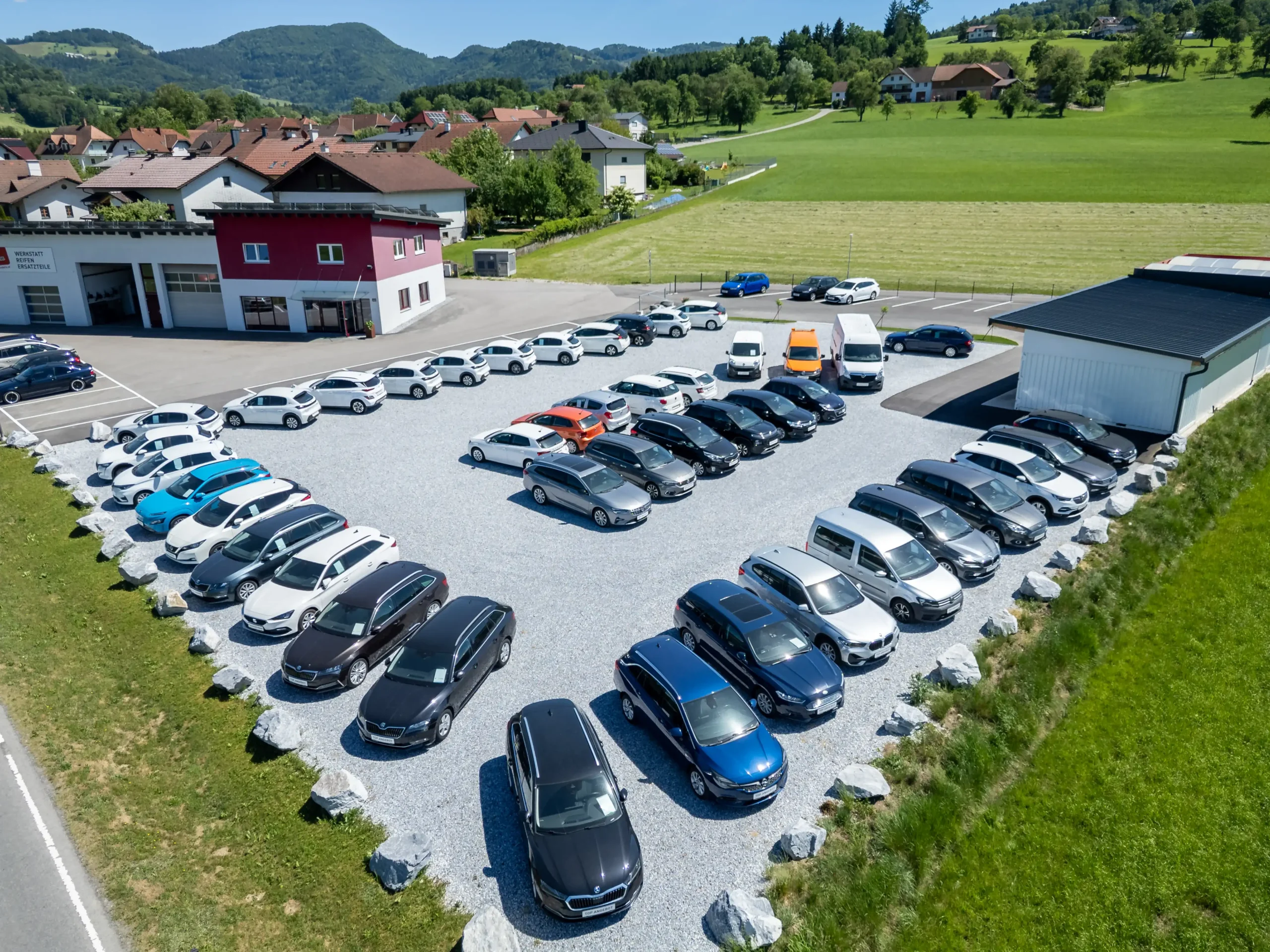 Luftaufnahme der Werkstatt und des Autohaus Comandella in St. Georgen an der Leys inklusive des Fuhrparks mit Neu- und Gebrauchtwagen.