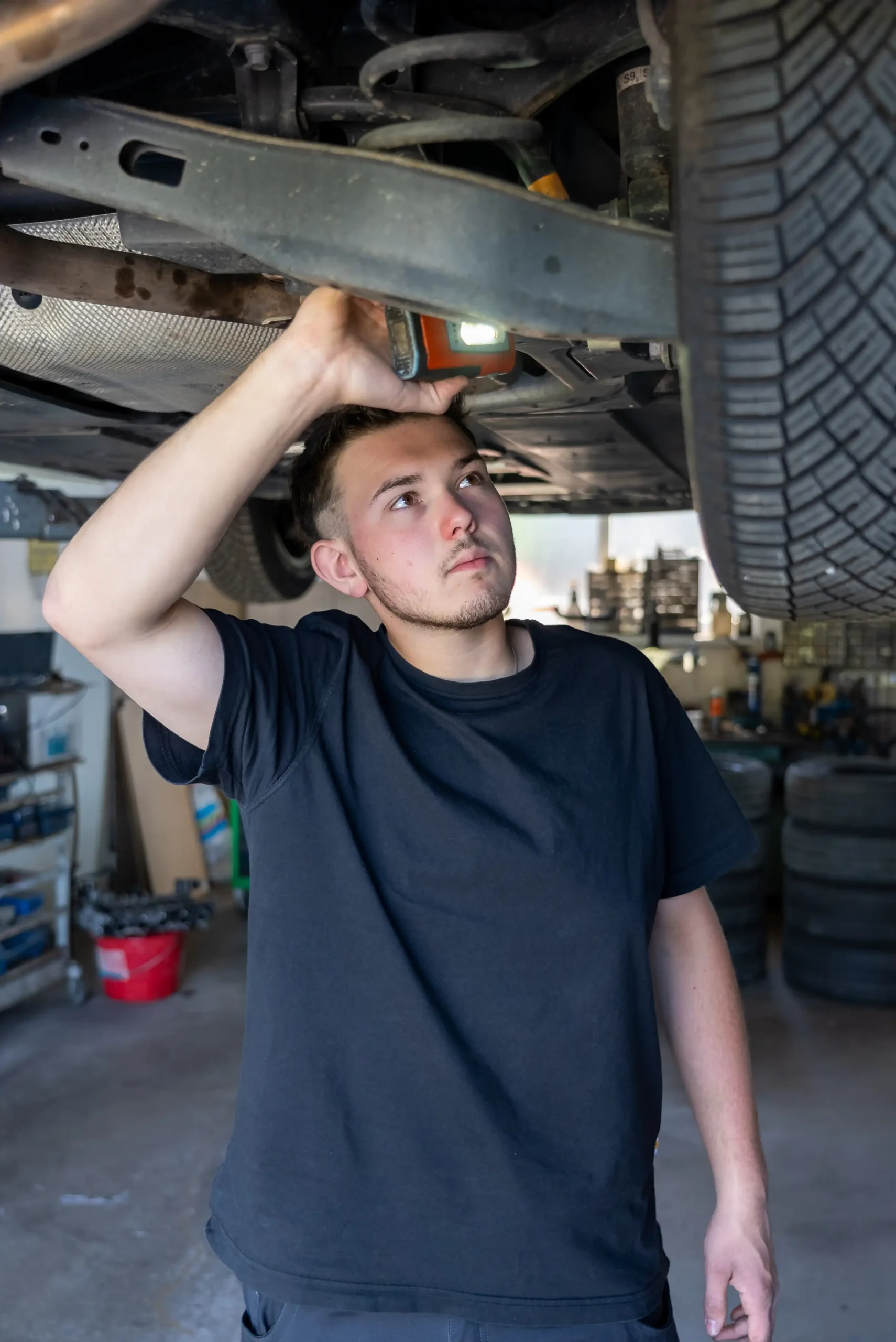 Ein Automechaniker führt Service oder Reparaturarbeiten an einem Fahrwerk in der Werkstatt des Autohauses Comandella durch.